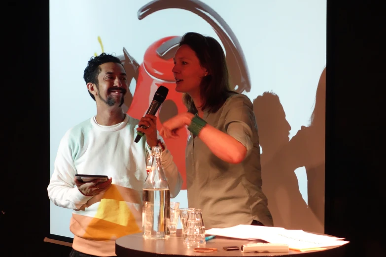 a man and woman speaking on stage with microphone