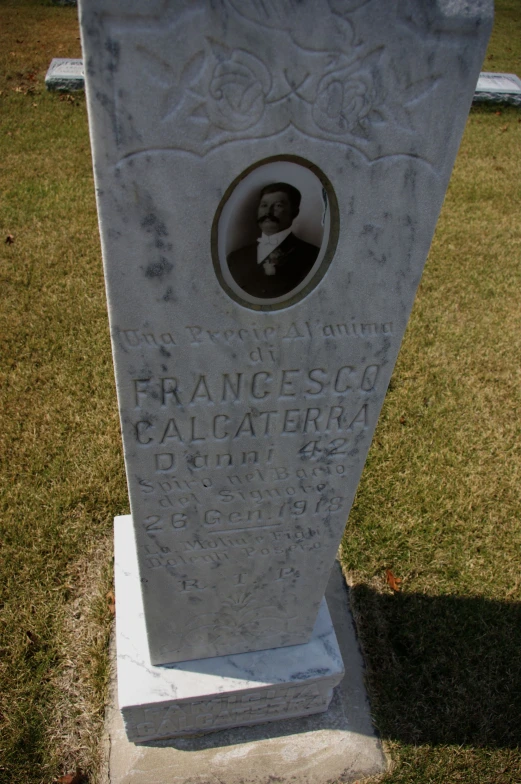 a monument in a park has an old picture embedded