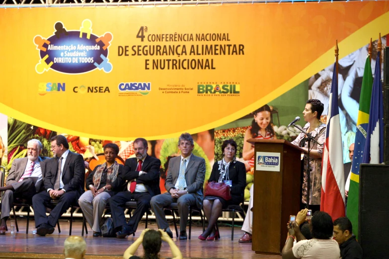 a group of people are sitting in a room while one man is speaking