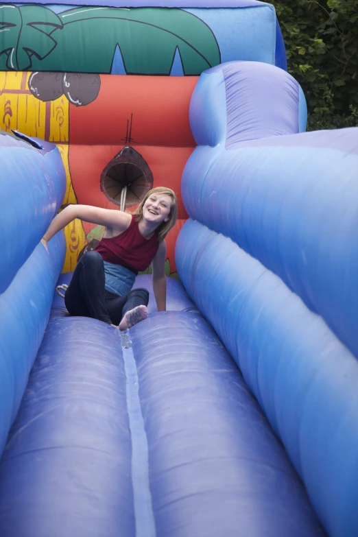 woman in red shirt sitting on blue inflatable obstacle course