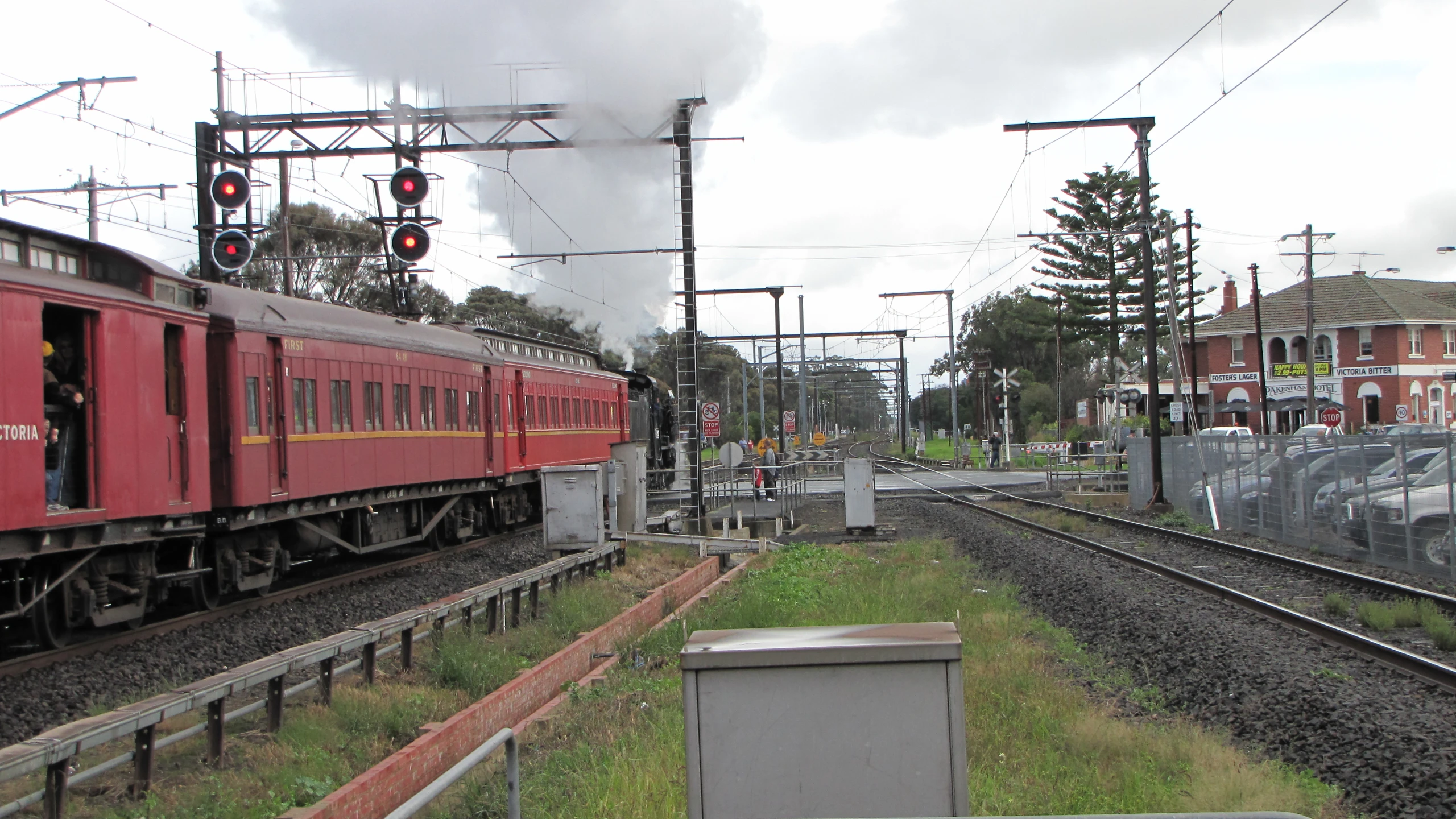 a red train with yellow trim moves past a stop light