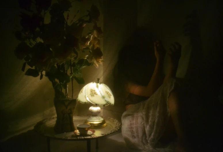 the woman lies in bed beside the lamp and has a candle