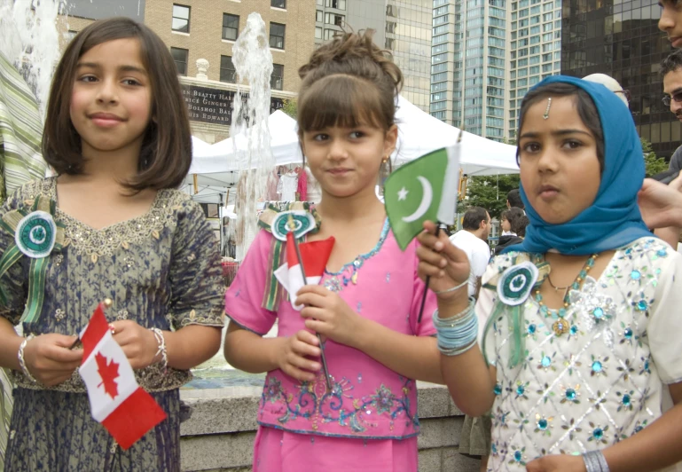 four people standing outside holding flags and water fountain