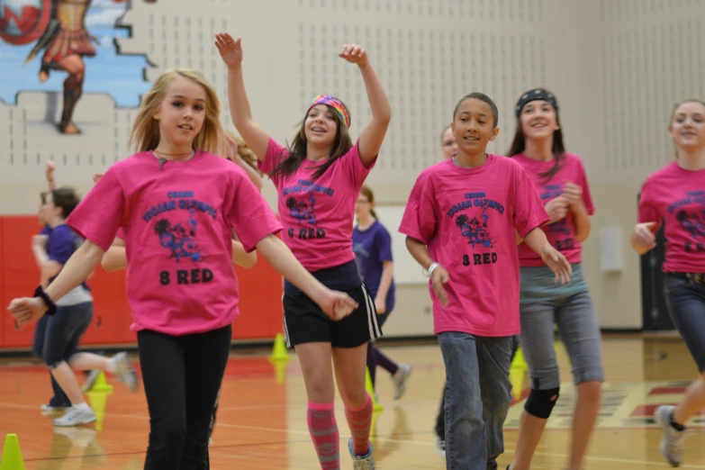 a group of girls wearing pink shirts doing exercises together