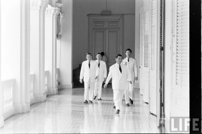 two men walking down a hall with other men in suits