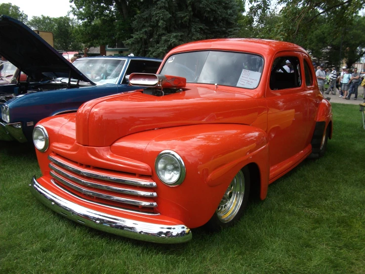 an old red truck parked on top of a green field