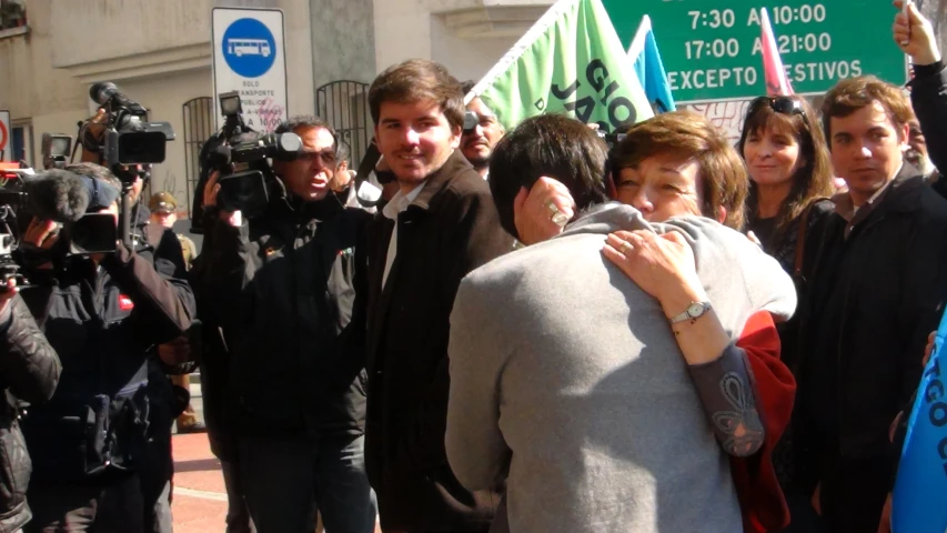 the man is hugging his lady outside by a large crowd