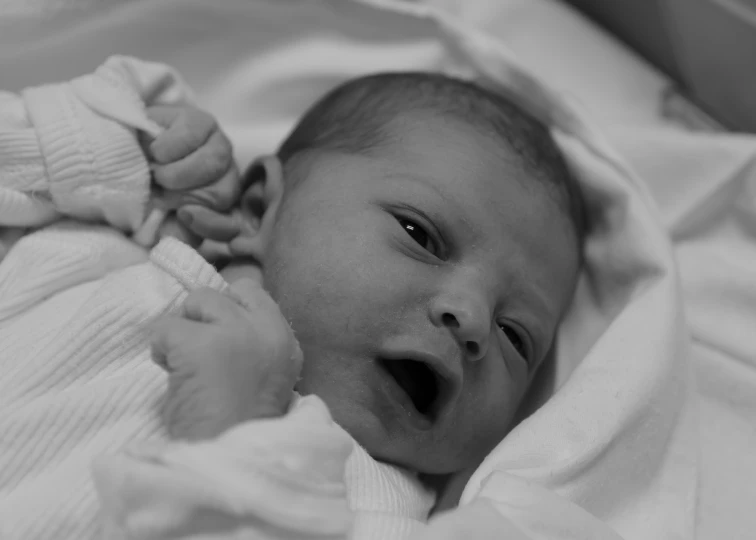 a baby in a hospital gown and smiling at the camera