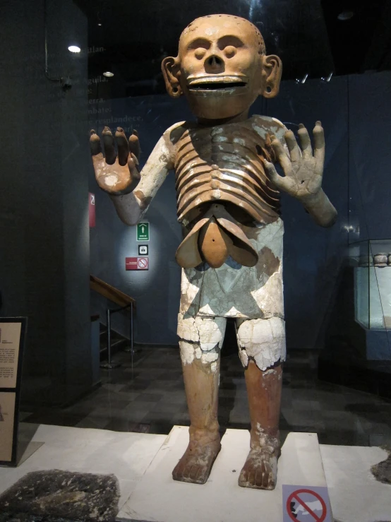 the statue is made of clay and features a skeleton in his right hand