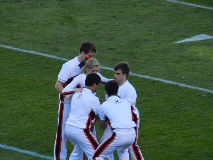 a group of soccer players huddle together in the midst of an action