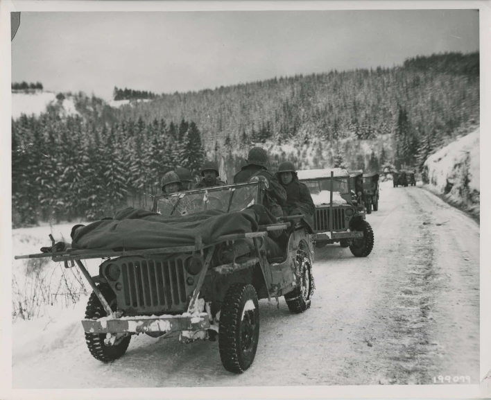 military vehicles traveling on road with snow covered hills in the background