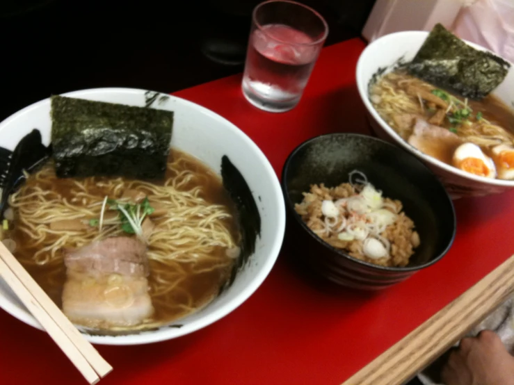 a red table topped with bowls of soup and plates of rice