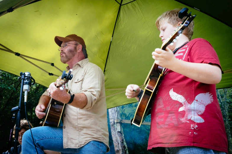 a man standing next to a little girl holding a guitar