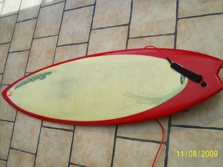 there is a red and white surfboard lying on the floor