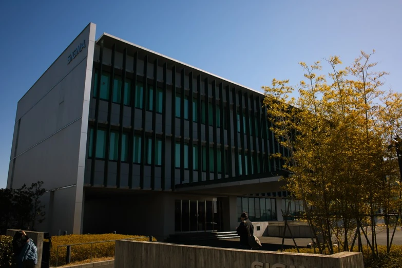 a large building that has green windows and a man walking in front