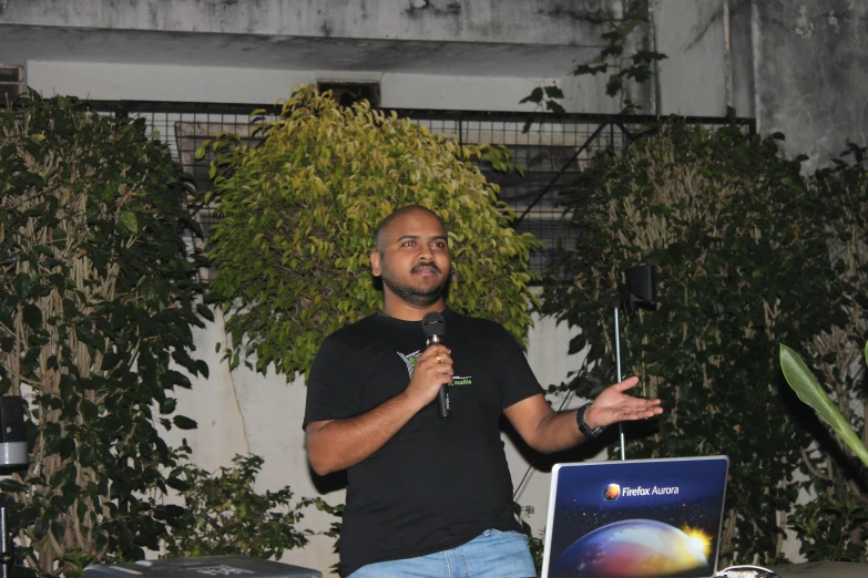 man giving a speech while holding a microphone in his hand