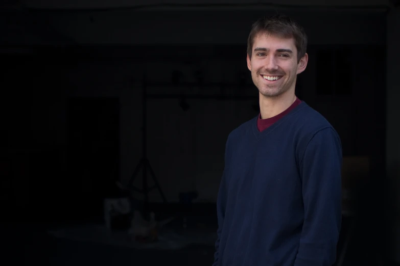 a man standing in a dark room smiling for the camera