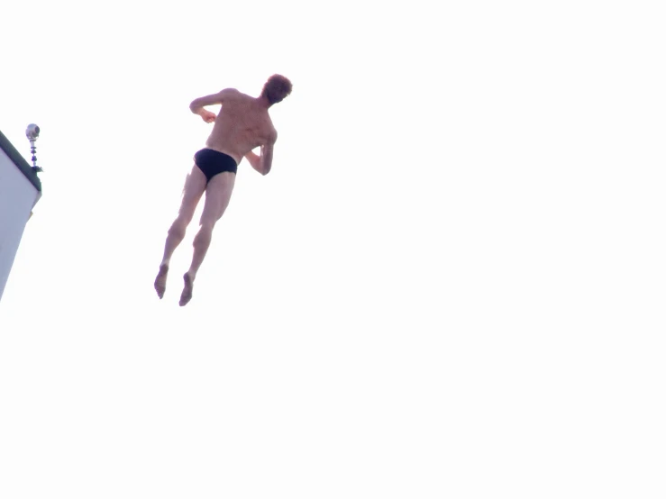 a shirtless man diving into the air in a swimming suit