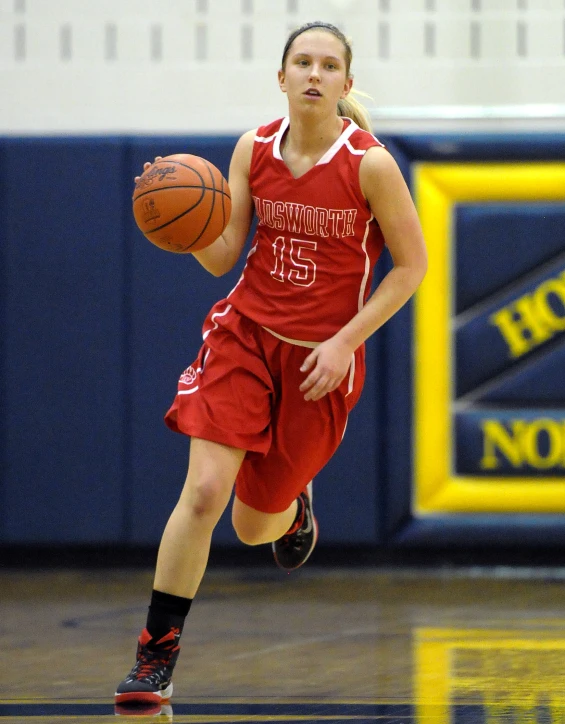 a young woman running down the court with a basketball