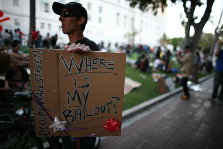 people on the side walk at a protest against ball and bat