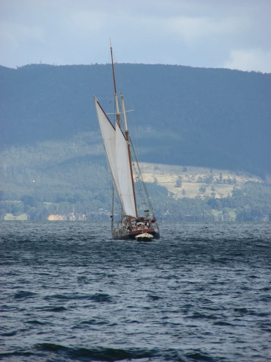 a boat with white sails on the water