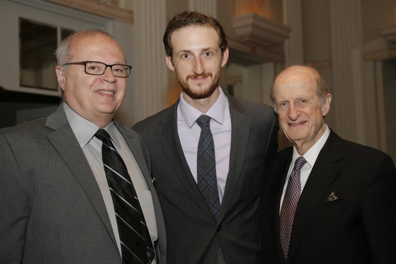 three men are posing together with one man in suit