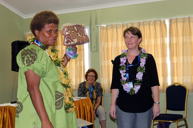 a woman in a lei standing next to a woman who is holding a plate