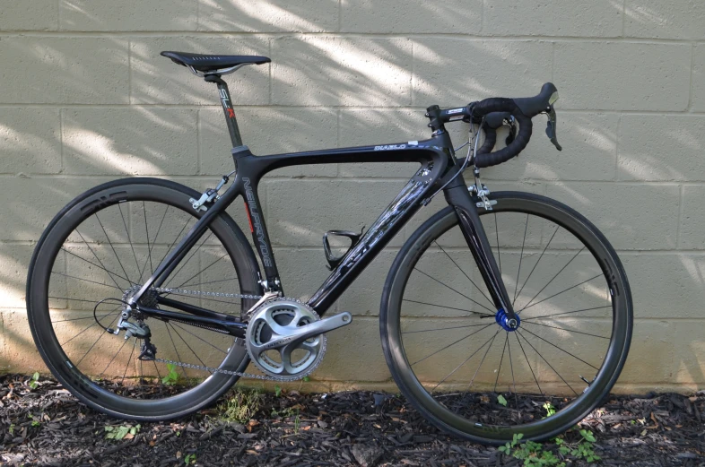 a black road bike against a wall in front of it