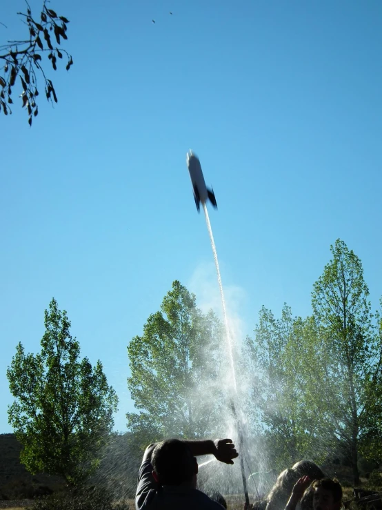 a woman and a boy watch an airplane fly through the air