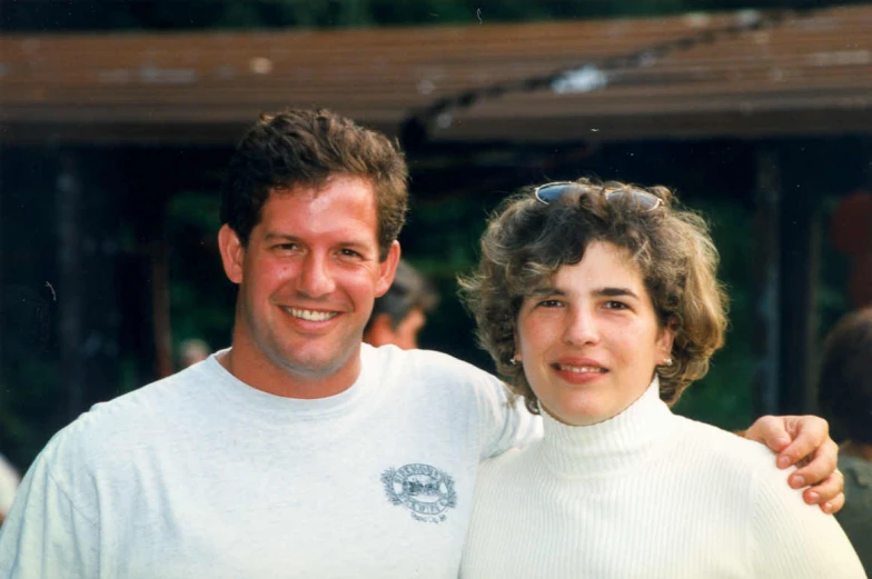 a woman standing next to a man wearing a white shirt