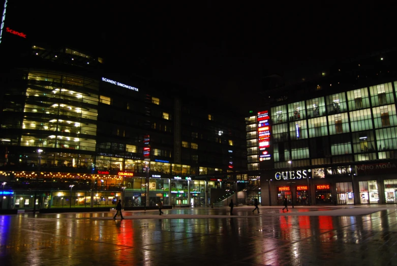 many illuminated buildings and people are walking on the street at night