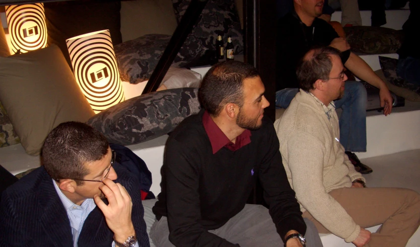 several men sitting on a floor looking in different directions