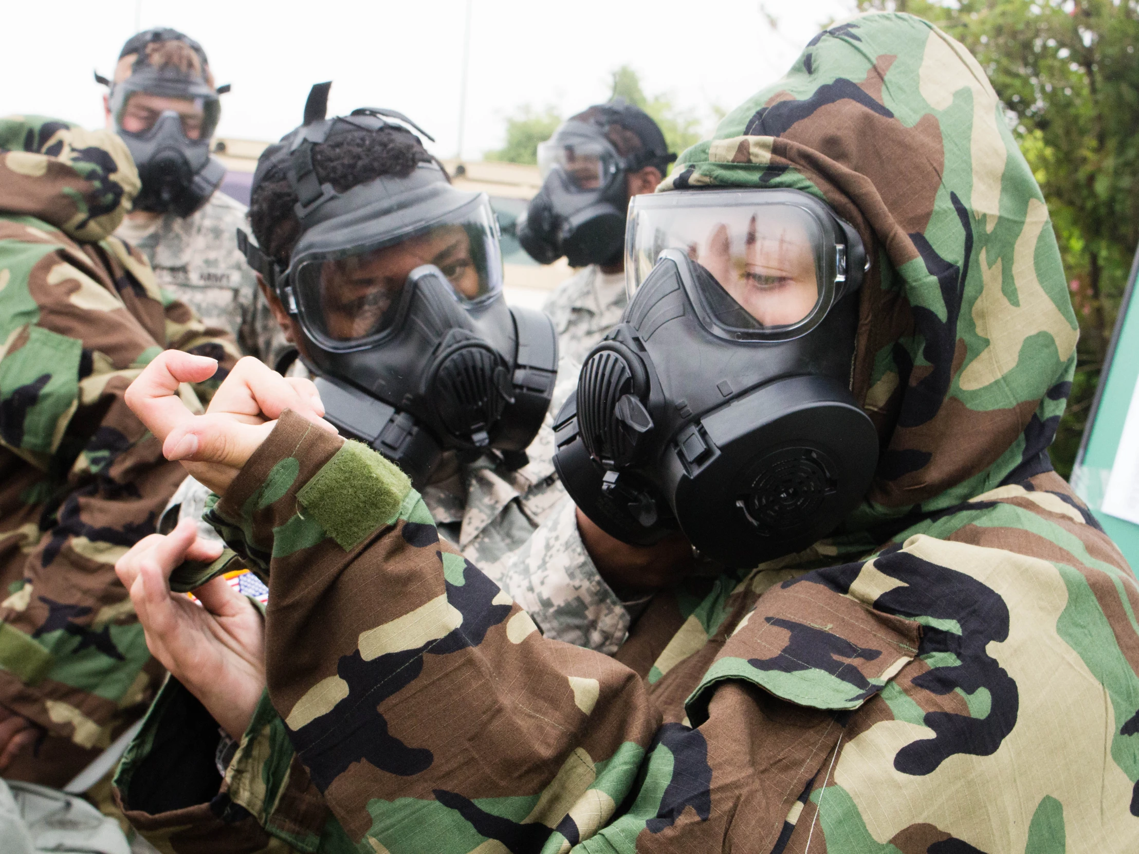 men in camouflage with gas masks talking to someone