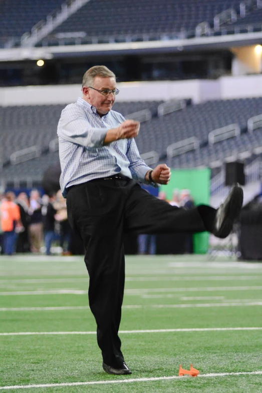 a man stands on a football field with his legs apart, with a camera in hand