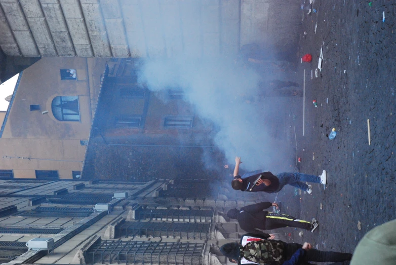 smoke rises in the street as the protesters run