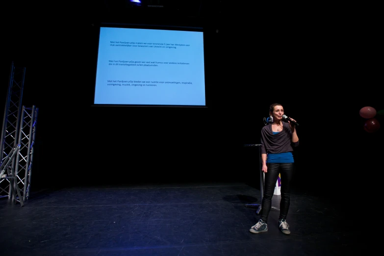 a woman standing in front of a projector screen holding a microphone