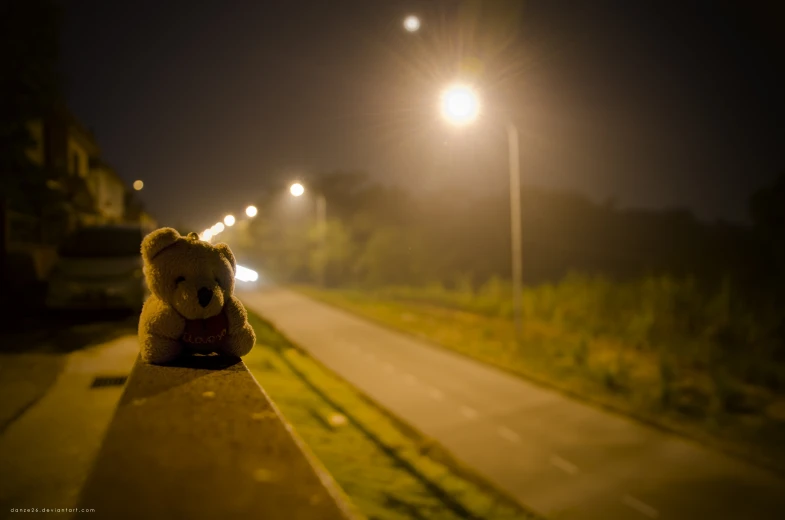 a teddy bear sitting on the edge of a cement block