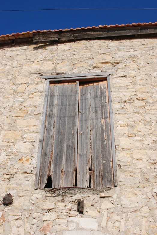 an old run down building with shutters in front of it