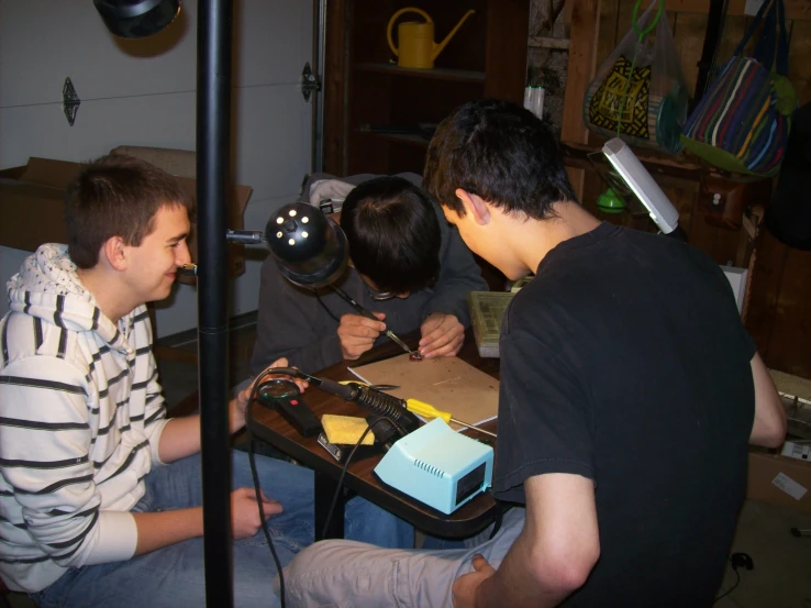 four boys are sitting around a table that has some sort of device on it