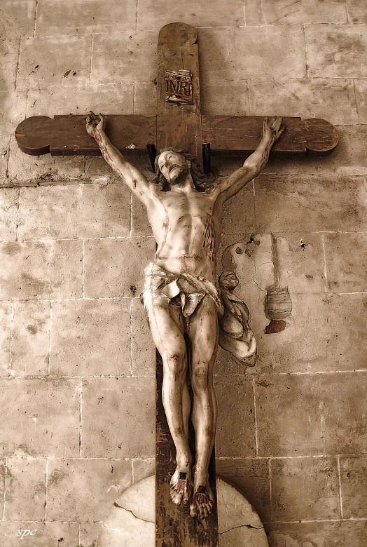 a jesus sculpture holding up a large wooden cross