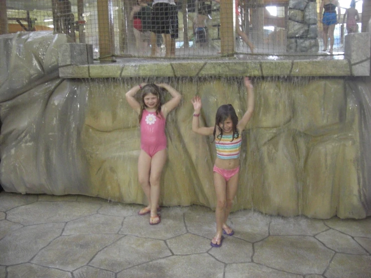 two girls are standing in front of a waterfall