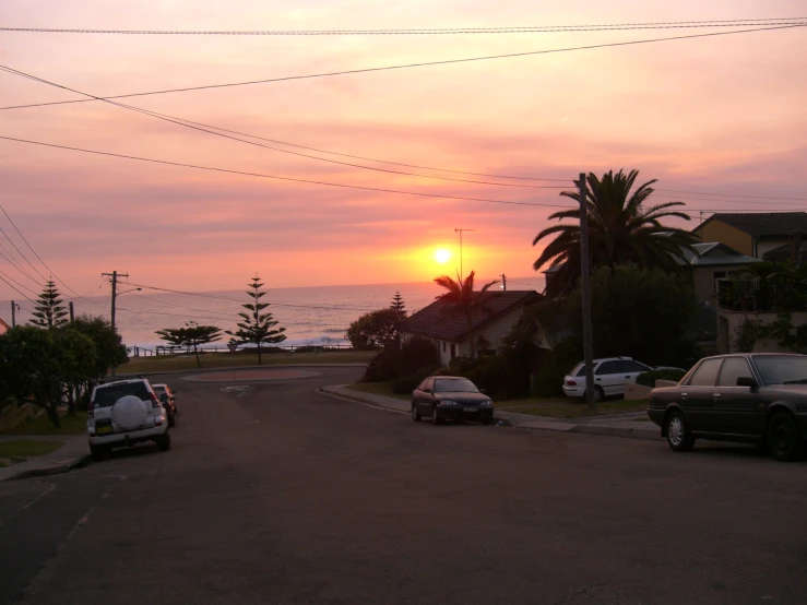 a sunset over the ocean with a city street in the foreground
