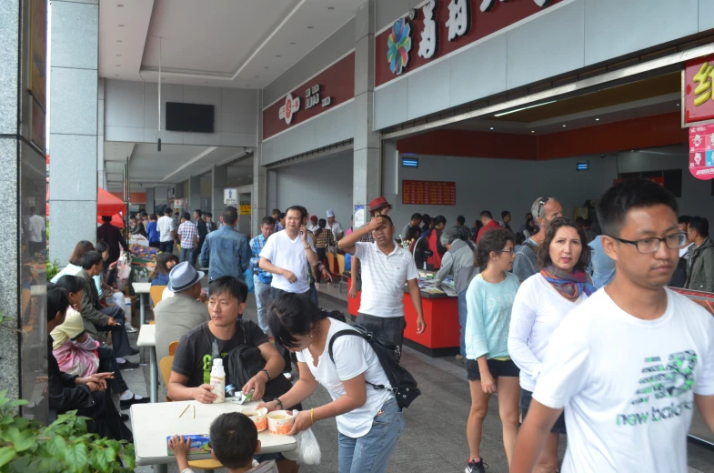 many people are standing in the mall eating food