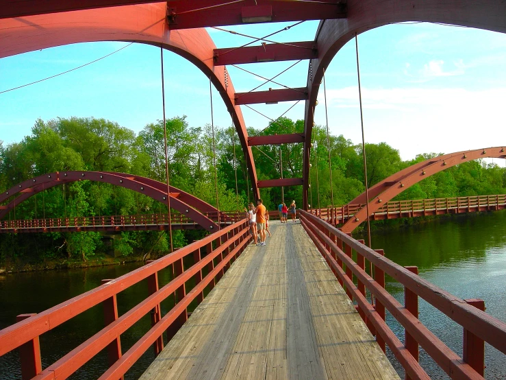 people walking across a bridge over a body of water