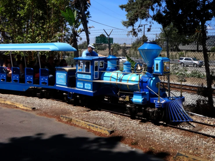 a blue train with people sitting on it on tracks