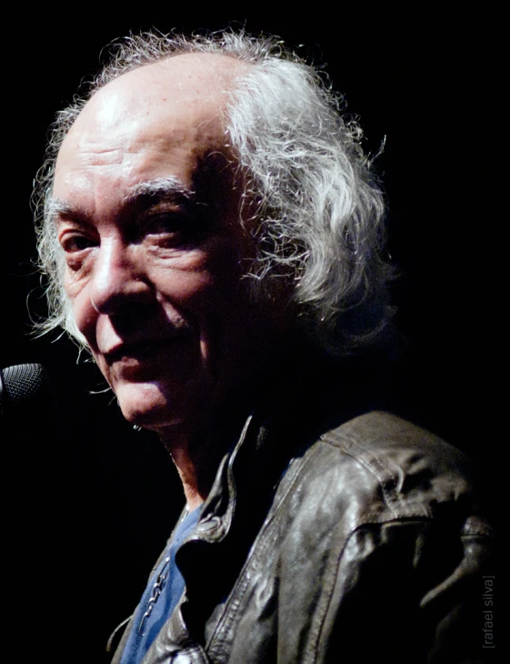 a man with long white hair standing next to a microphone