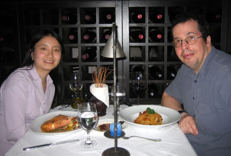 man and woman sitting at table in front of bottles of wine