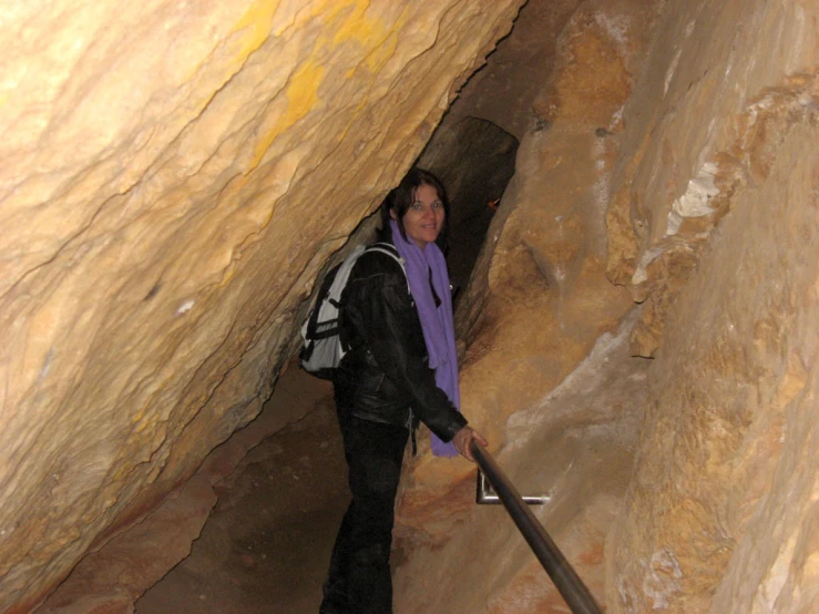 a person standing in a cave with a backpack and umbrella