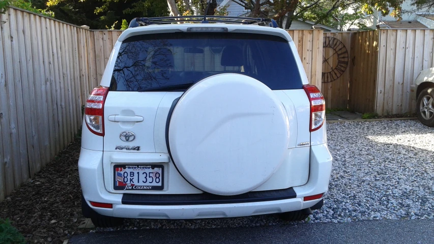 a white suv with a large surfboard on top of it's bumper