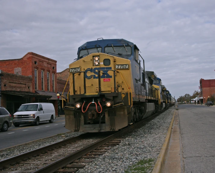 a train sits on the tracks with traffic near by